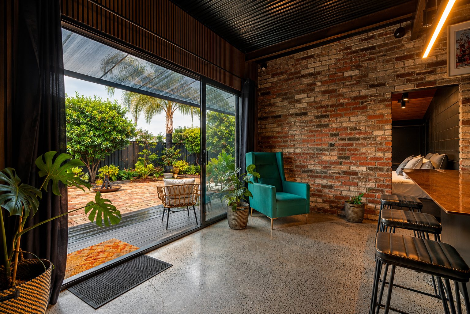 The Midnight Hideaway – exposed brick lounge with polished concrete floor and lush garden outlook